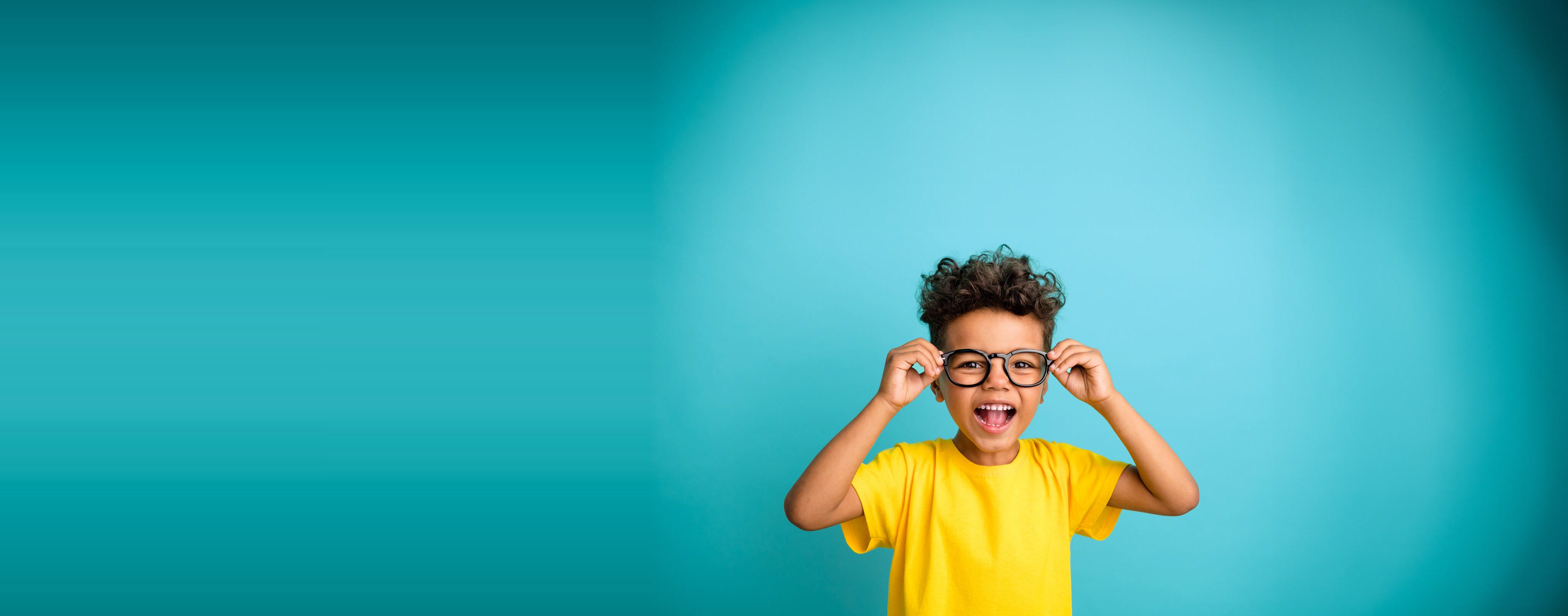 A child laughing, wearing glasses, on an AngelQ turquoise field
